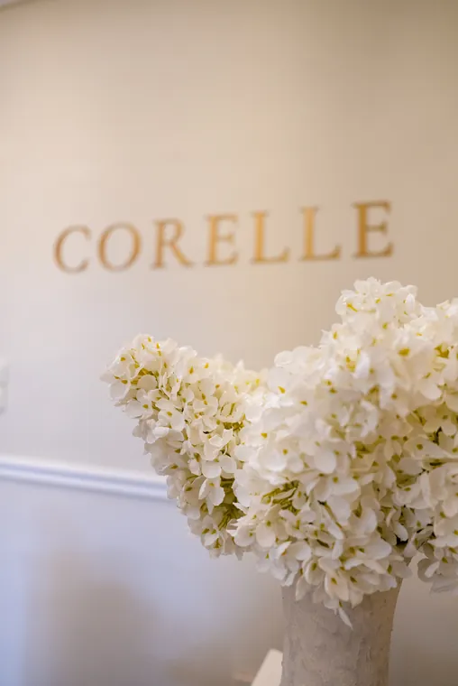 A CORELLE felirat a falon, fehér virágokkal